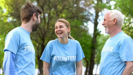 Obraz premium Group of eco volunteers laughing at park, enjoying made work, nature care
