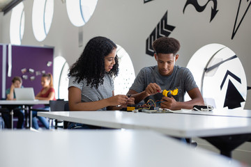 High school students working on a robotic arm in class