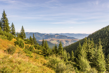 Scenery of the Carpathians centered between two hills shot from the top of the mountain on a bright September day
