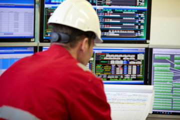 Energy industry. Digital control of heating system. A technician dressed in red overalls and a...