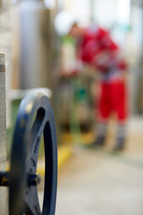 Heating valve control wheel. Blurred background. A technician in red overalls is servicing heating technology. Start of hot water supply into  big city heating network. Heating season coming.