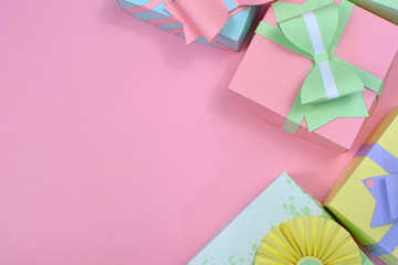 Flat lay background with pastel colored paper craft gift boxes with ribbons right side and copy space of pink background © Firn