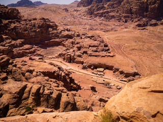 View of the valley of the historic site of Petra, Jordan, orange desert full of temples and a roman amphitheatre, seen from aerial perspective from a sandstone mountain