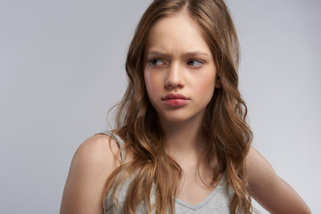 Fototapeta premium Upset teen girl standing against gray-white background