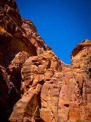 Orange walls of a canyon in the historic sight of Petra, Jordan, in the mountains of the desert under blue sky