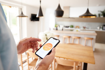 Close Up Of Man Using App On Smart Phone To Control Central Heating Temperature In House © Monkey Business