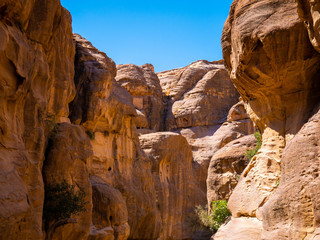 High sandstone mountains as walls of a canyon in the valley of Petra, Jordan