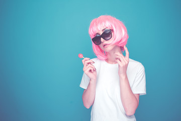 Bautiful 90s girl in a whit t-shurt and black glasses with lollipop in a blue room