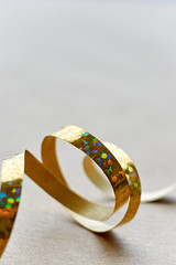 Golden curly ribbon on brown kraft paper background. Serpentine with curls for use as a christmas, anniversary, marriage, wedding or celebration background. Vertical with copy space.