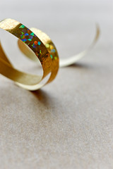 Golden curly ribbon on brown kraft paper background. Serpentine with curls for use as a christmas, anniversary, marriage, wedding or celebration background. Vertical with copy space.