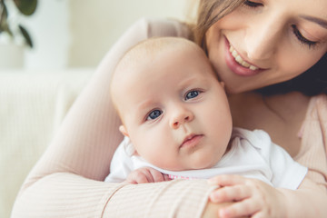 cropped view of mother holding her child in apartment