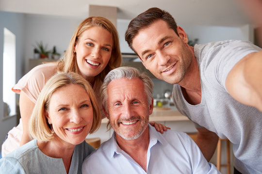 Senior Parents With Adult Offspring Posing For Selfie At Home