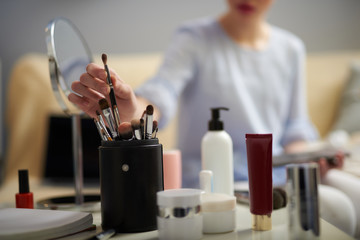 Young lady taking cosmetic brush for applying eyeshadow