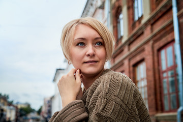 Blonde funny pretty girl near wall with red brick in Central part of old city. Portrait of girl on street