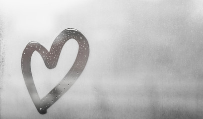 Gray heart painted on sweaty glass, there are many drops on it, inscription heart and love using...