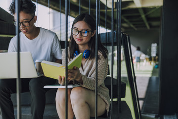 Young Asian students studying together on stairs