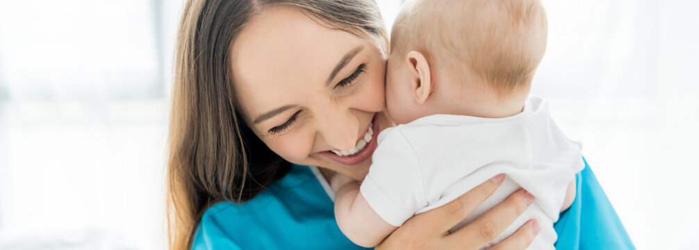  Panoramic Shot Of Attractive And Smiling Mother Holding Her Child In Hospital