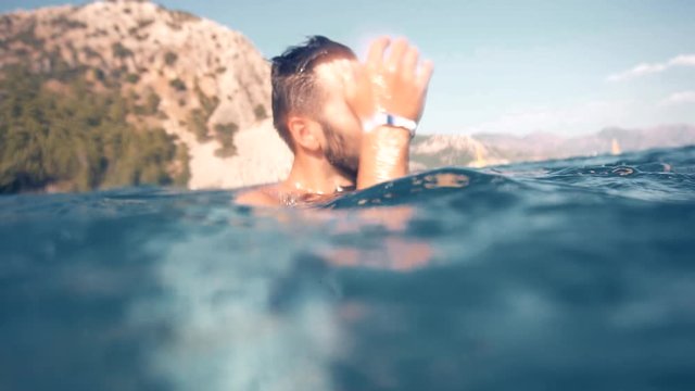 Swimming Man On Blue Sea Underwater.Underwater Man Swimming In Slow Motion With Air Bubbles.Air Bubbles In Water.Water Drops Falling And Splashing On Glassy Water Surface Blue Ocean.