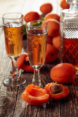 Apricot liquor and fresh apricots on a old wooden table.