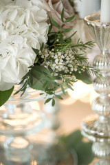 Wedding table setting is decorated with fresh flowers and white candles. Wedding floristry. Bouquet with roses, hydrangea and eustoma. Table numbering