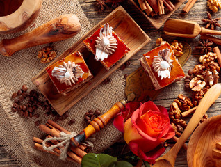 Layered cakes with cinnamon, anise, coffee beans and nuts on a old wooden table.