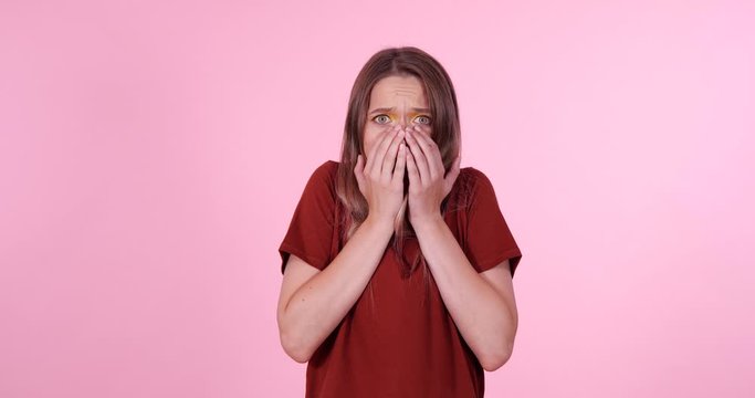 Shocked teenage girl on light pink background