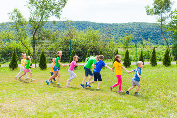 Fototapeta premium Kids running holding hands at the lawn