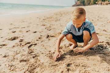 Little boy playing on a sandy beach in the summer