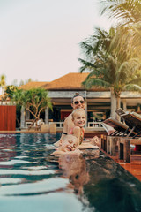 Smiling mother and adorable children relaxing in a resort pool
