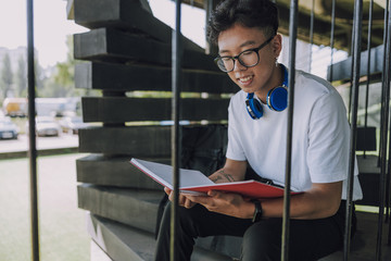 Good-looking male student with headphones reading his project