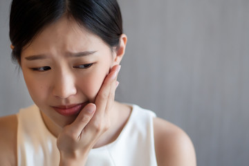 woman with toothache; sick asian woman suffering from toothache, tooth decay, tooth sensitivity, cavity, dental care concept; young adult asian woman model