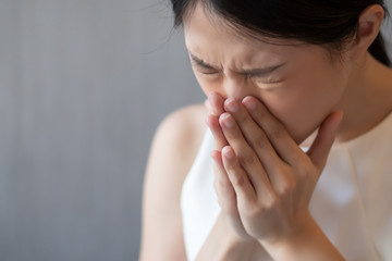 asian woman sneezing; concept of health care, body care, sickness, cold, flu, allergy, hay fever, rhinitis symptoms