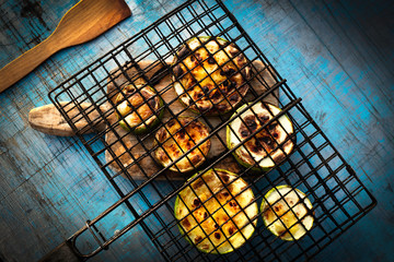 Charcoal baked zucchini round slices on a blue wooden background .