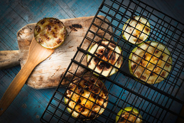 Charcoal baked zucchini round slices on a blue wooden background .