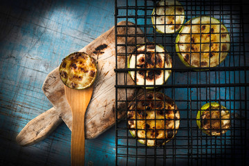 Charcoal baked zucchini round slices on a blue wooden background .