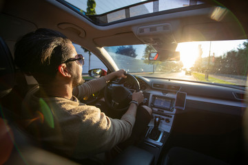 Handsome young man driving his car into the sunset