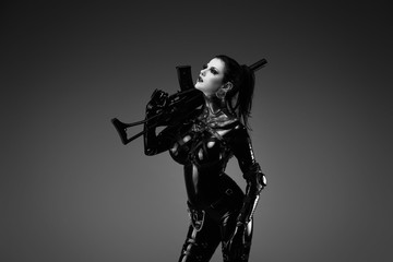 Portrait of a young woman in latex jumpsuit holding a machine gun in her hands	