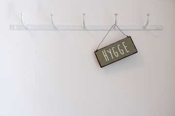 Schild mit dem dänischen Wort Hygge an einer wand mit Kleiderhaken