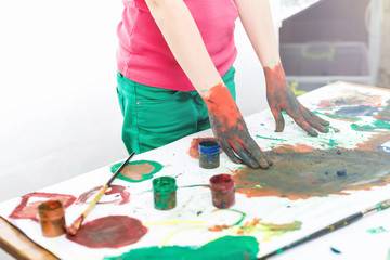 red hands in paints on background of light table painted in different colors