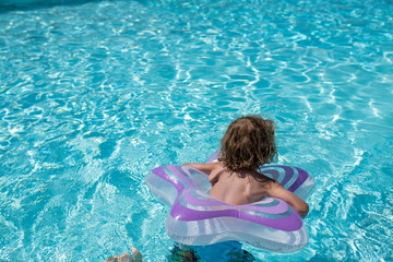 kind im sonnenbeschienen Pool mit schwimmring