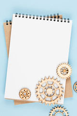 gears made of wood on blank sheet of notebook top view