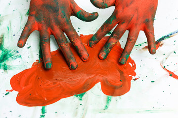 red hands in paints on background of light table painted in different colors