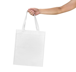 Mockup of female hand holding a blank Tote Canvas Bag isolated on white background.