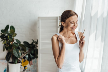 smiling young woman holding pregnancy test at home