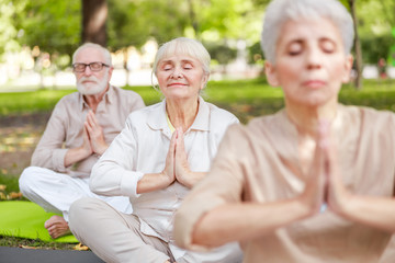 Old people meditating in lotus position outdoors