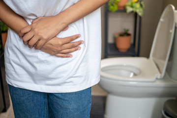 woman with diarrhea symptom; sick woman suffering from diarrhea, stomachache, menstrual period cramp, abdominal pain, food poisoning, gastritis, constipation; asian young adult woman health care model