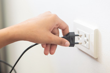 using electricity wall outlet with wet hand; electrocute danger concept