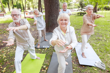Smiling old people doing qigong exercise outdoors