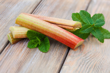 Fresh rhubarb and mint leaves on a wooden table