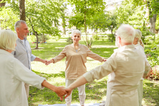 Smiling old people standing in healing circle and holding hands
